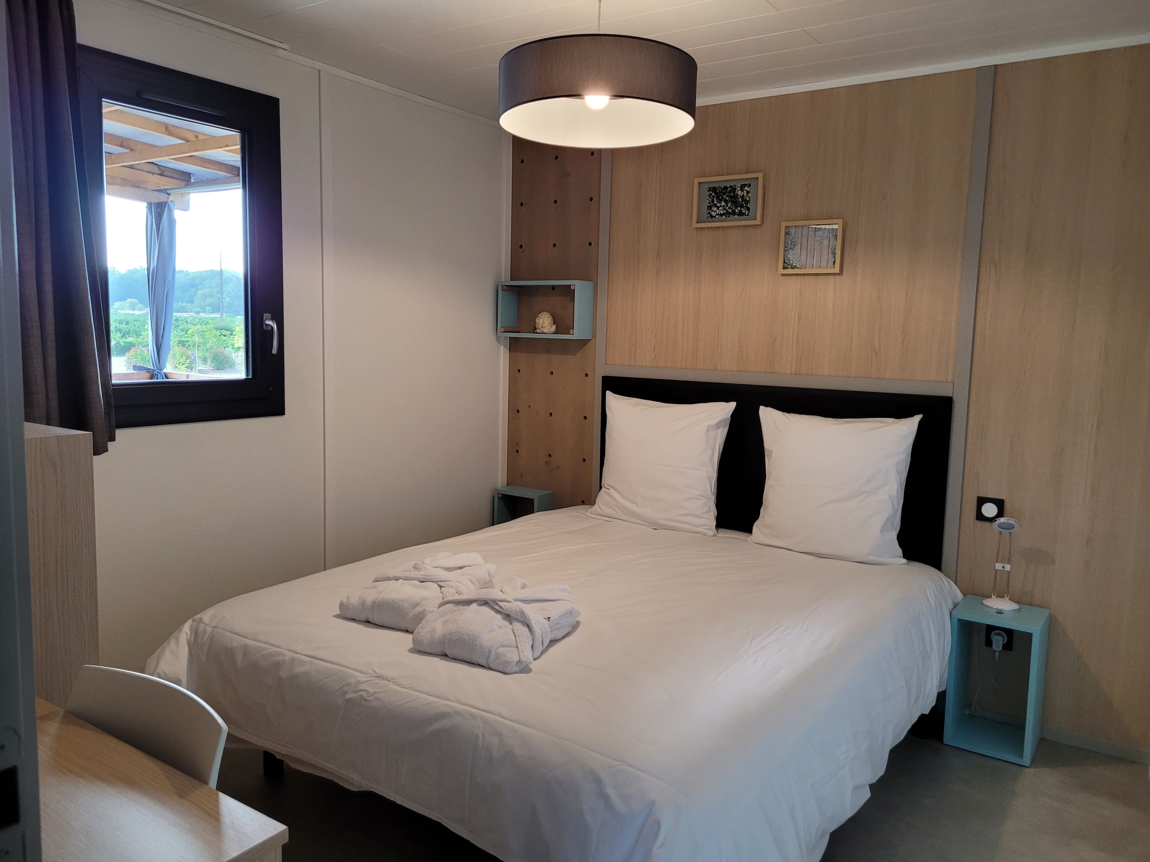 Chambre confortable d'un chalet en Dordogne Brantôme avec un lit double et une vue sur la nature.
