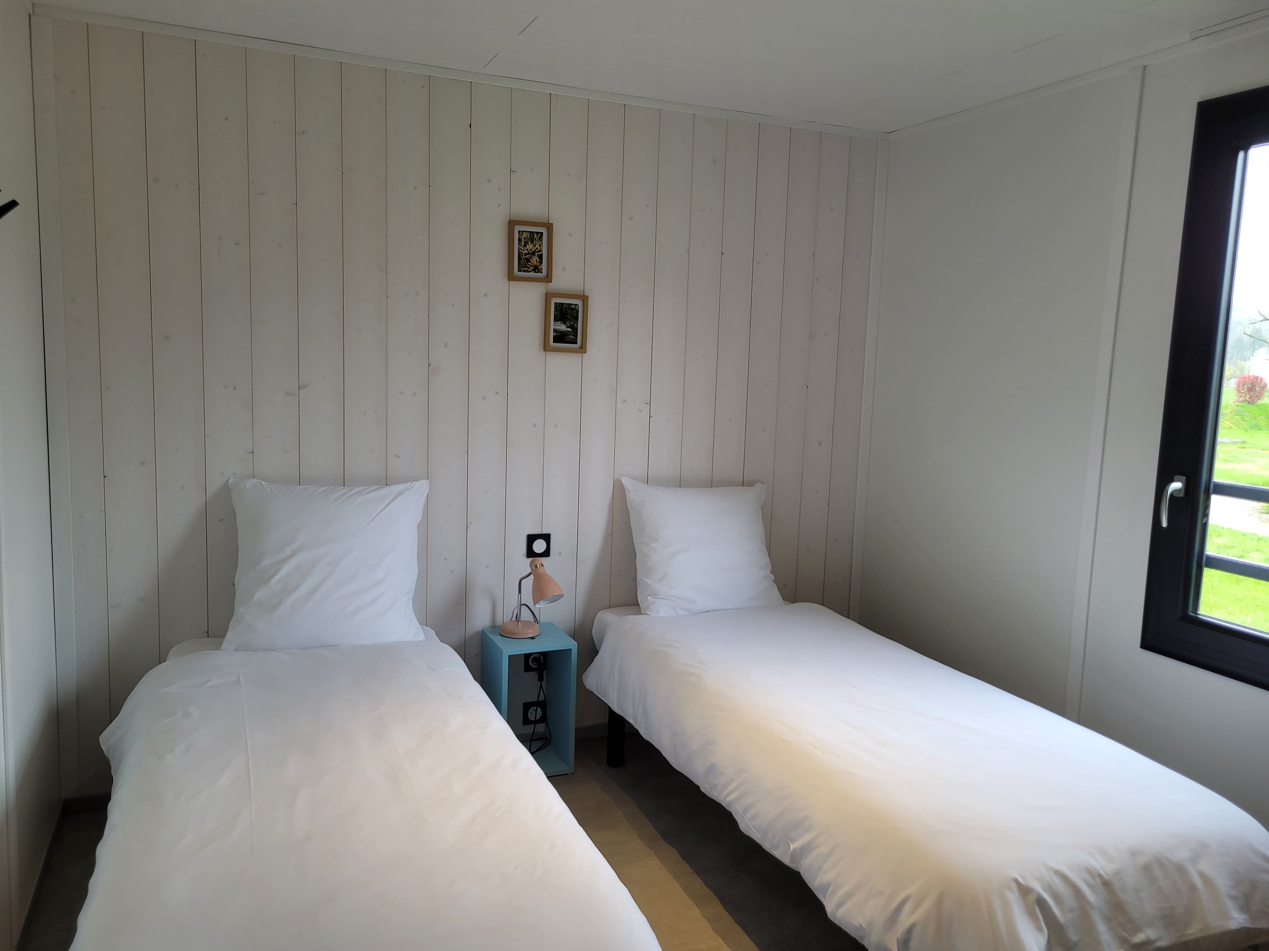 Deux lits confortables dans une chambre avec vue sur la campagne verdoyante de la Dordogne Périgord.