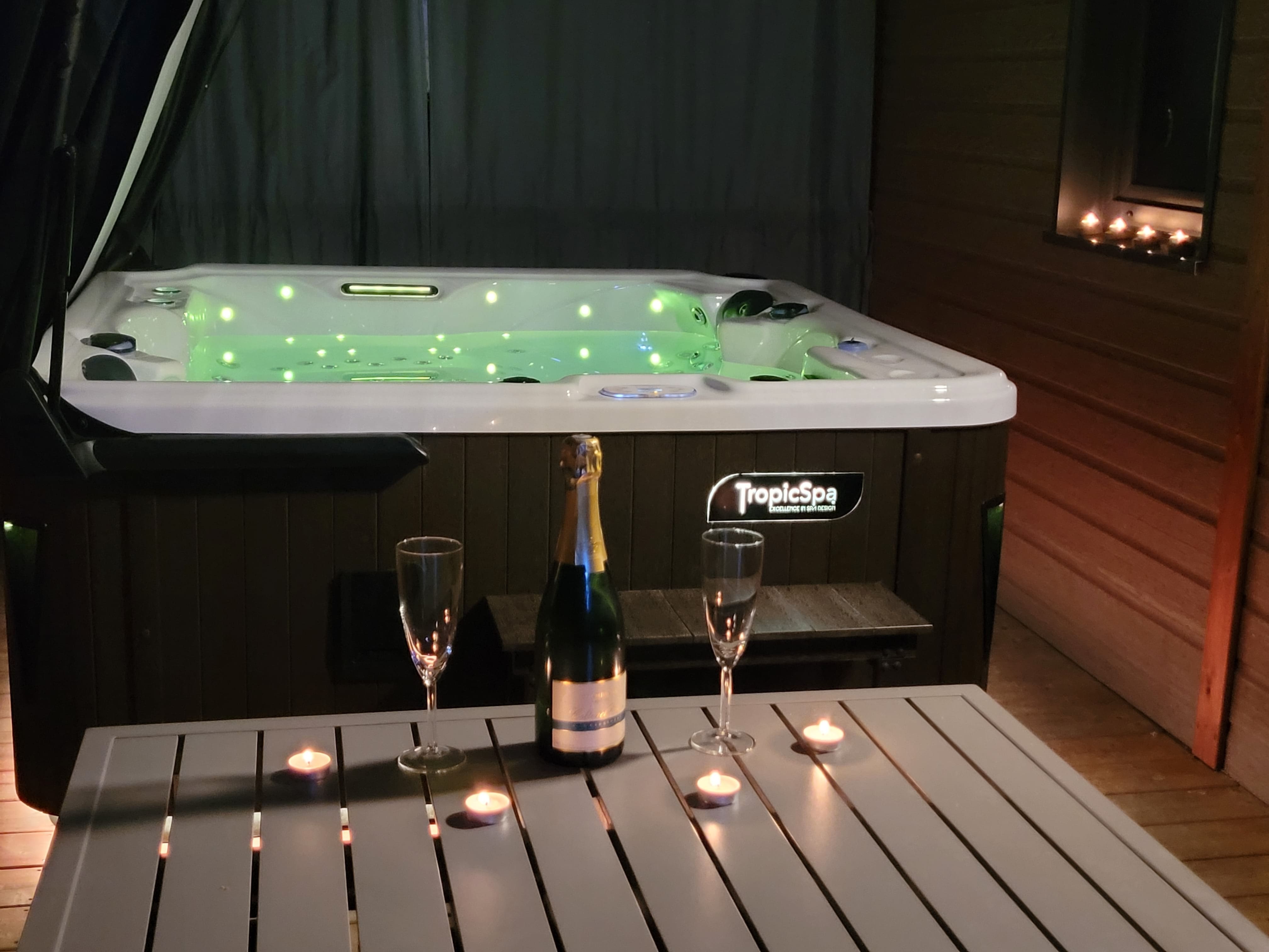 Espace intime et chaleureux d'un spa en soirée, avec champagne et bougies pour une ambiance relaxante et romantique.